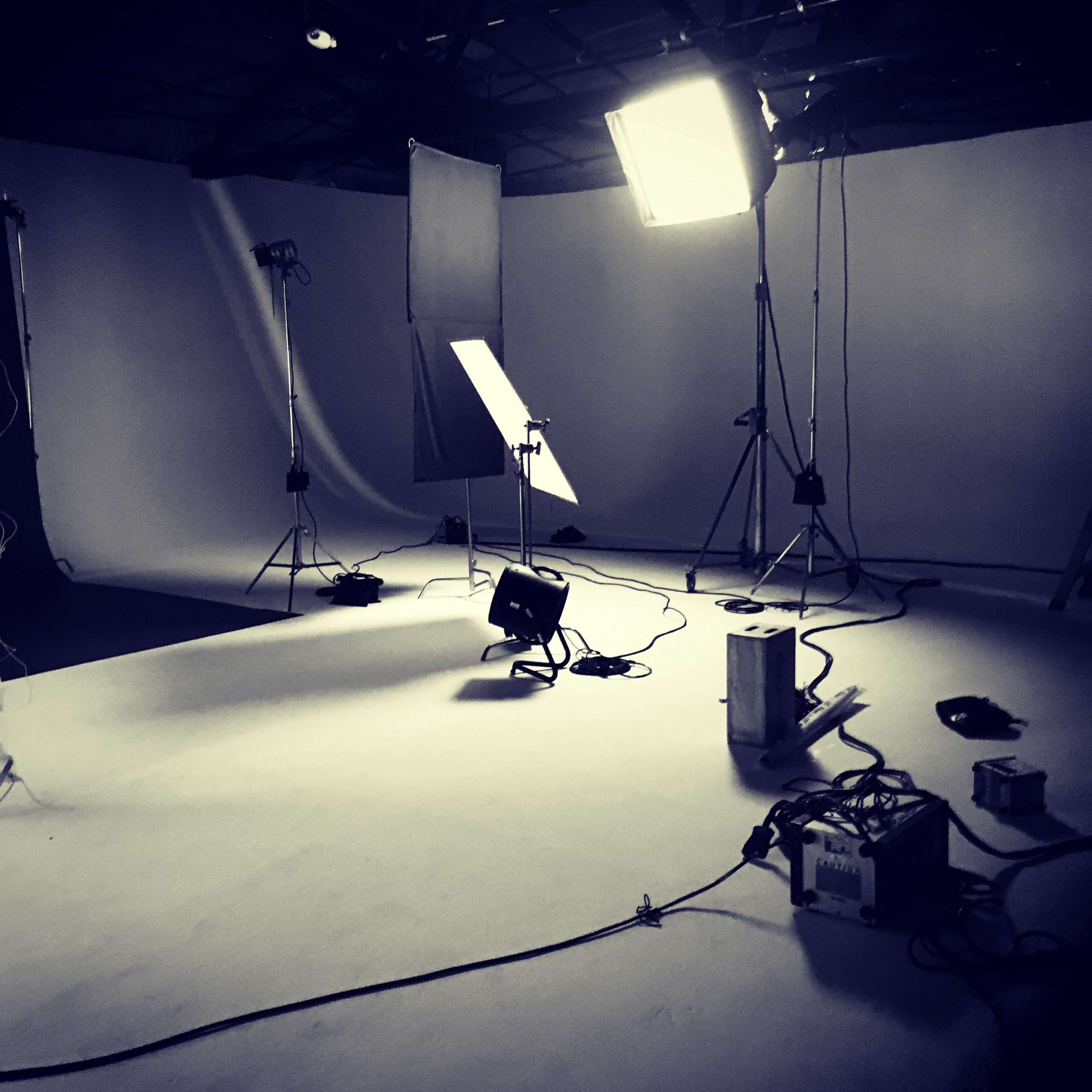 A diverse film crew watching playback on monitors during a live set, lit by teal and magenta production lights